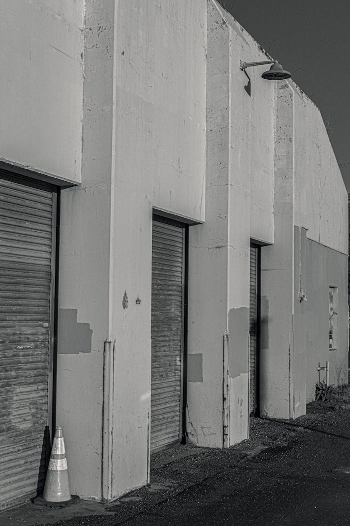 Black and white image of an industrial warehouse with roller shutters in a vertical shot.