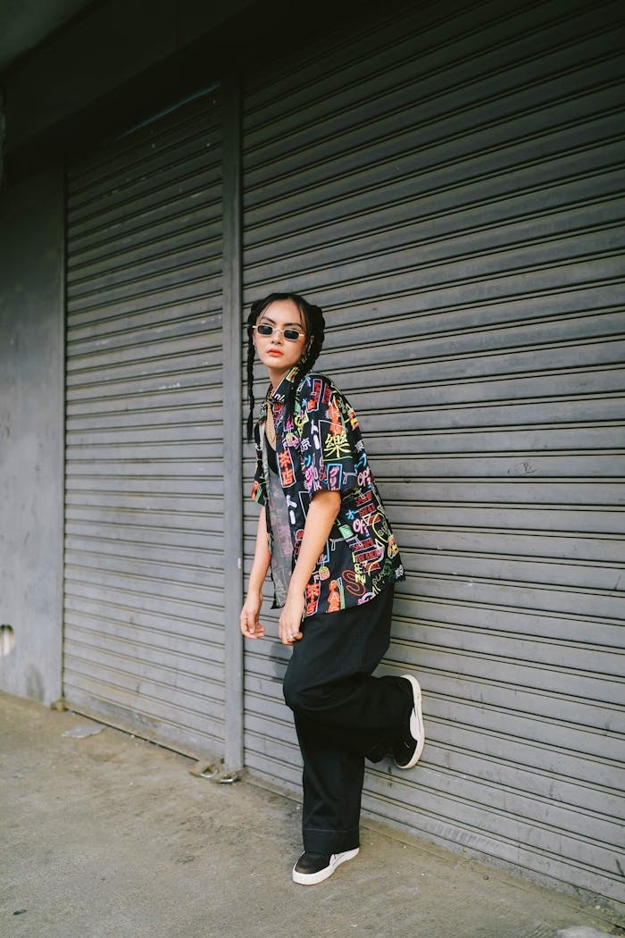 Fashionable young woman posing outdoors against urban roller shutters.