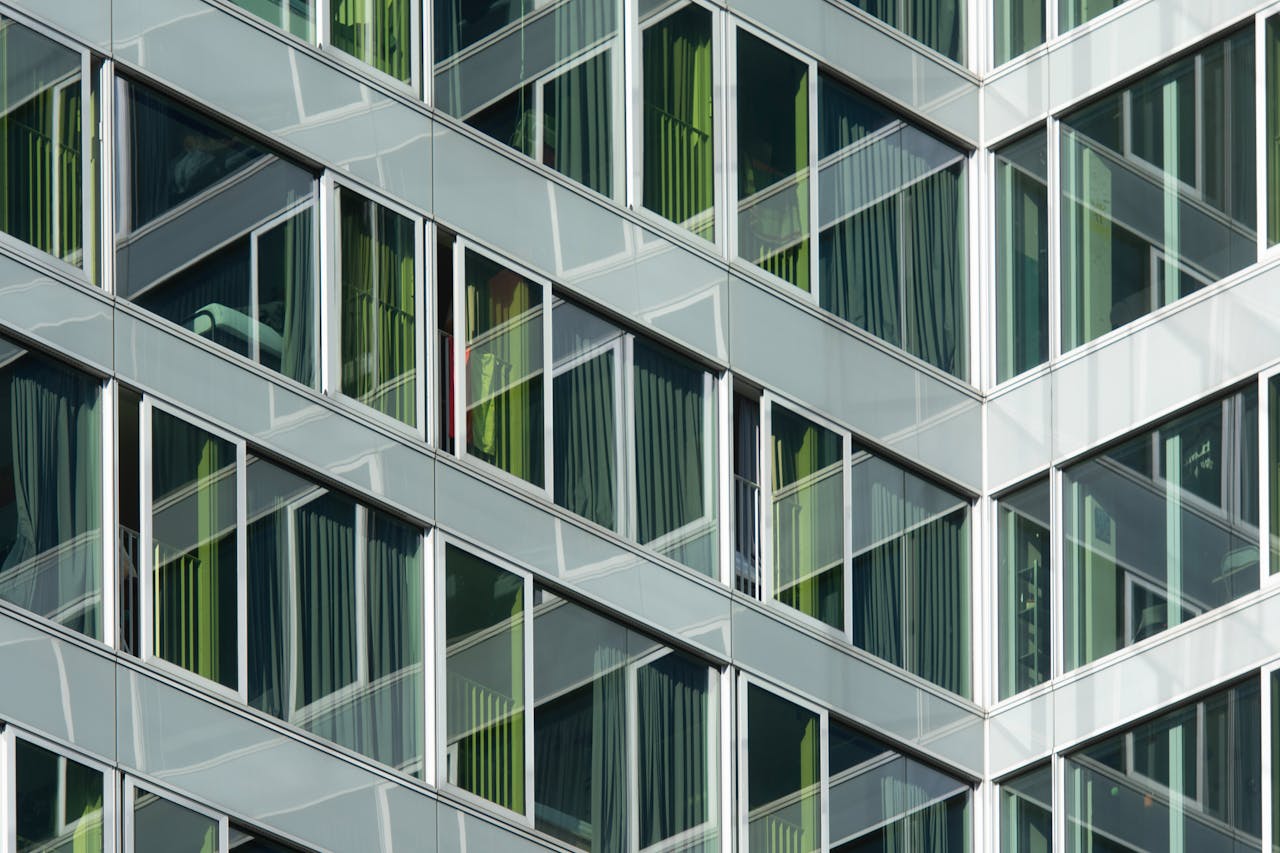 A modern building with a geometric glass facade featuring reflective windows and curtains.