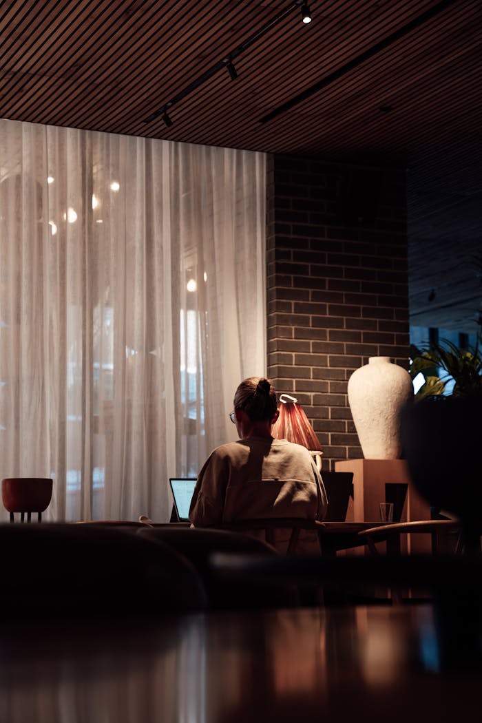 A person working on a laptop in a warmly lit cafe in London, England.