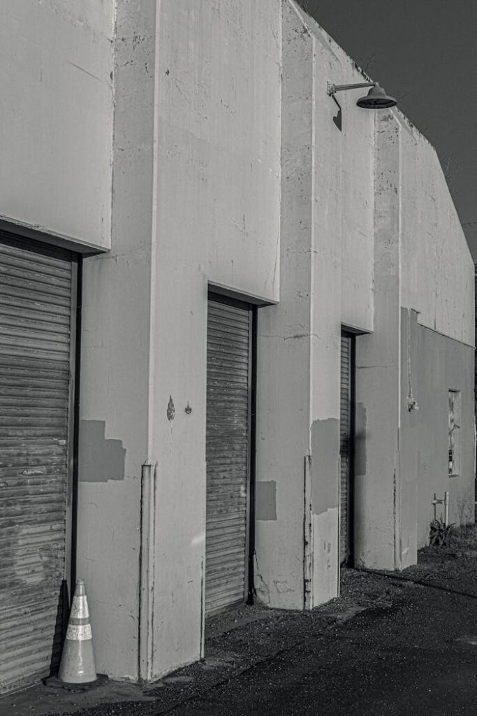pexels-photo-10319310-1 Black and white image of an industrial warehouse with roller shutters in a vertical shot.